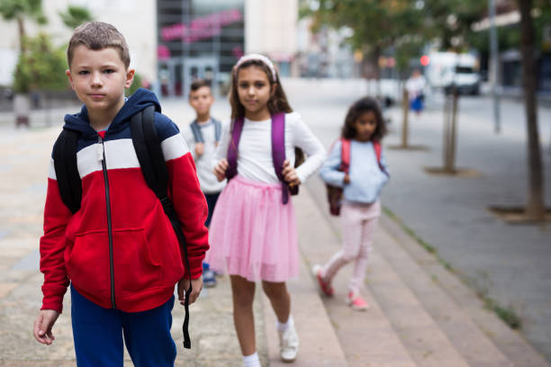 istock Positive boy standing near school, children on background 1285920370