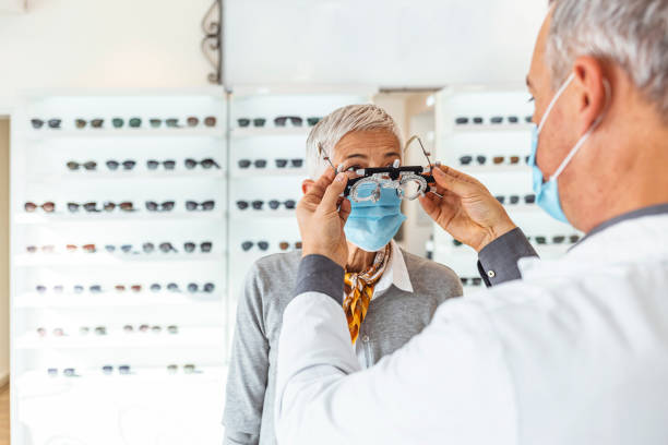oftalmologista fazendo um exame de visão de uma mulher idosa com quadro de ensaio - patient senior adult optometrist eye exam - fotografias e filmes do acervo