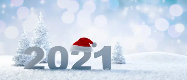 Numbers 2021 with Santa Claus hat standing in the snow with sparkling blue background