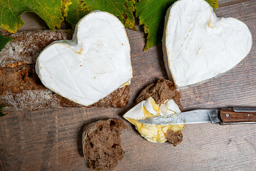 a French Neufchatel cheese shaped heart on wooden background