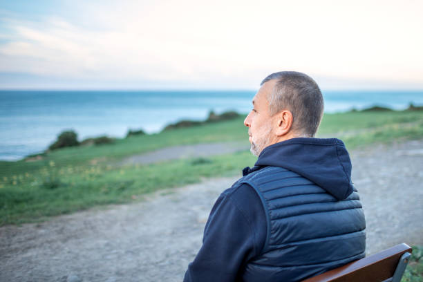 istock Mature man sitting on a bench by the sea 1285924732