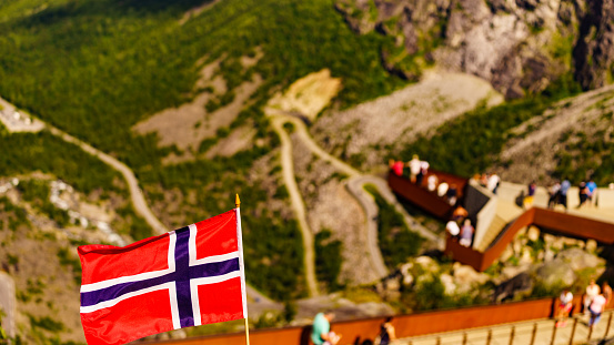 Norwegian flag with typical norwegian red wooden house with sod roof on Lofoten islands