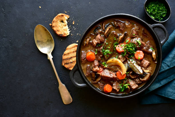 beef bourguignon - meat stew with vegetables and mushrooms with red wine in a skillet - caldo imagens e fotografias de stock