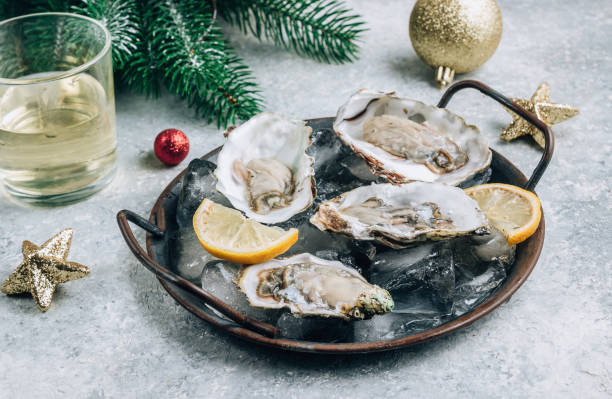 お祝いの装飾が施されたコンクリートの背景にレモン、氷、白ワインの牡蠣。 - prepared oysters ストックフォトと画像