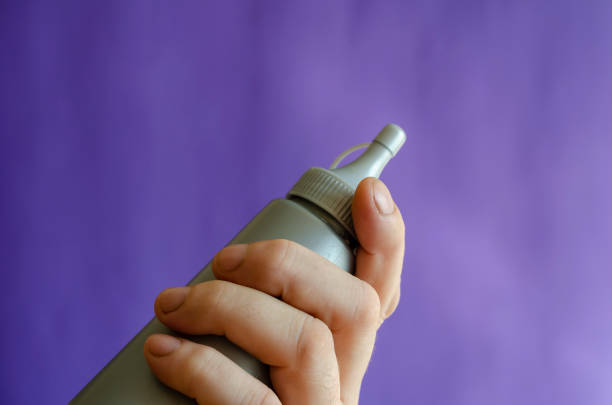 istock Male hand and gray plastic bottle of syrup. 1285930647
