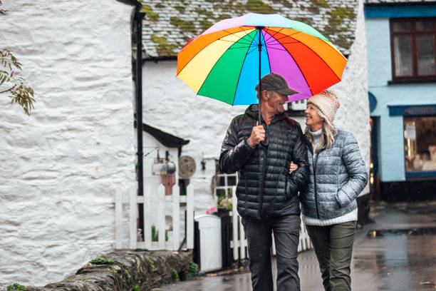 stroll through town in the rain - umbrella senior adult couple autumn imagens e fotografias de stock