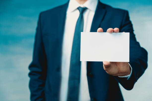 Male hand of a businessman in a blue suit with a tie holds an empty sheet in hand and shows it to the camera closeup Male hand of a businessman in a blue suit with a tie holds an empty sheet in hand and shows it to the camera closeup. male is standing and shows outstretched hand with open palm stock pictures, royalty-free photos & images