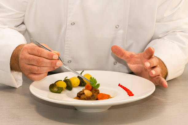 istock Selective focus of male chef's hands decorating a beef stew plate with parsley using pliers. Healthy and traditional food concept. 1285934259