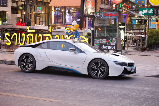 BMW i8 Hybrid sport car parked in Bangkok on Wanghin road in front of a restaurant. Behind is aDuffy the Duck statue. A person is on terraceof restaurant