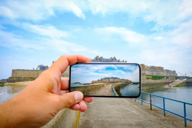 Taking a picture using a mobile smartphone of the walled city of Saint-Malo on the coast of Brittany, France. The fort is a medieval fortress with a turbulent history and is currently a popular tourist attraction.