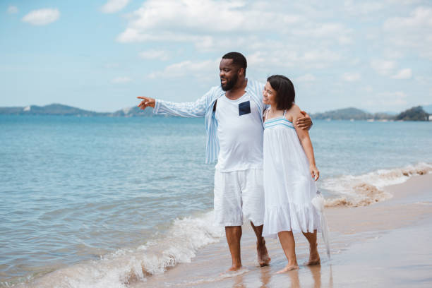 istock Romantic African American couple laughing and having fun together while walking on the beach 1285940547