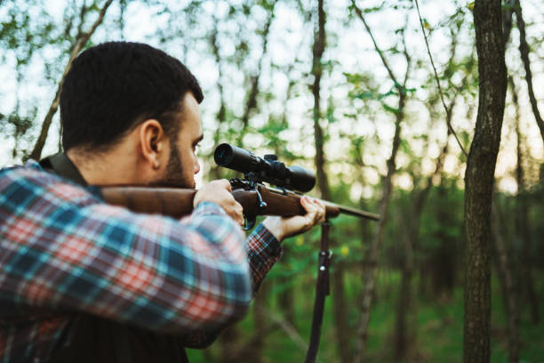 istock Portrait of hunter aiming with sniper rifle in the forest. 1285942113