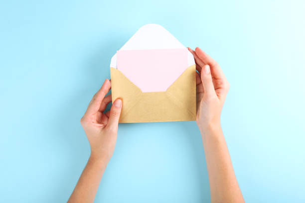 istock Paper envelope for letters on a colored background in women's hands 1285944087