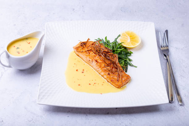 salmone con salsa ber blanc, spinaci e limone. decorato con porri. piatto tradizionale francese. - main course salmon meal course foto e immagini stock