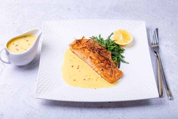 Salmon with Ber Blanc sauce, spinach and lemon. Decorated with leeks. Traditional French dish.