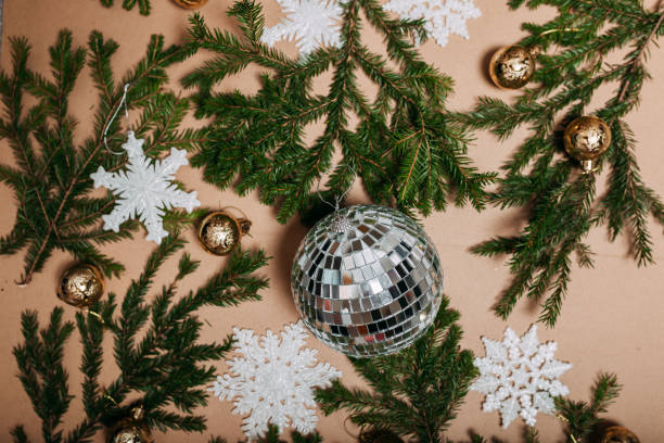istock Christmas decorations flat layout with many fir branches on the cardboard background. Disco ball in the center. Eco-friendly christmas ornaments. Scandinavian christmas cards with fir branches and snowflakes. 1285945079