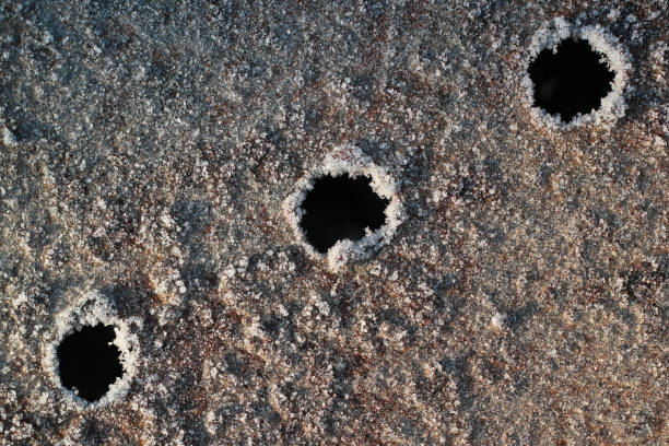 Three bullet holes in a metal plate covered with snow