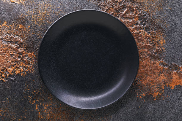 istock Empty black spotted plate on the table, top view. Food background 1285947152