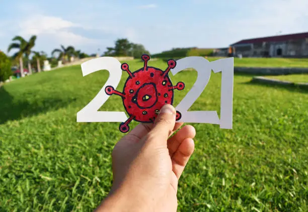 Photo of Happy new year 2021 concept with  hand holding text and corona virus hand drawn