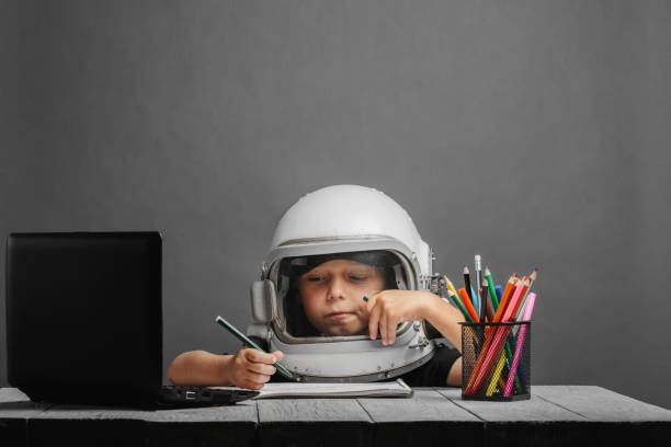 the child studies remotely at school, wearing an astronaut's helmet. back to school stock photo