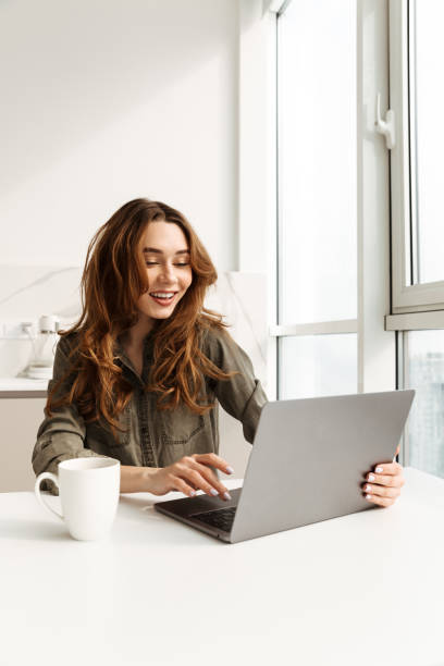istock Image of successful business woman sitting in hotel kitchen, and using notebook while drinking cup of tea or coffee in morning 1285952954