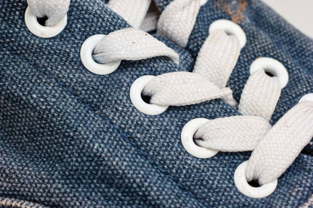 Old blue jeans fabric sneakers shoe lace holes close up macro shot Old blue jeans fabric sneakers shoe lace holes close up macro shot. eyelet stock pictures, royalty-free photos & images