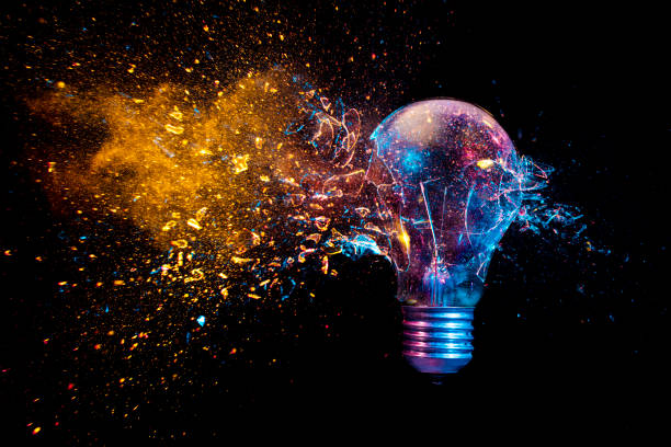 explosion of a traditional electric bulb. shot taken in high speed explosion of a traditional electric bulb. shot taken in high speed, at the exact moment of impact. Colored lights and black background. concept of creativity and fragility. invention stock pictures, royalty-free photos & images