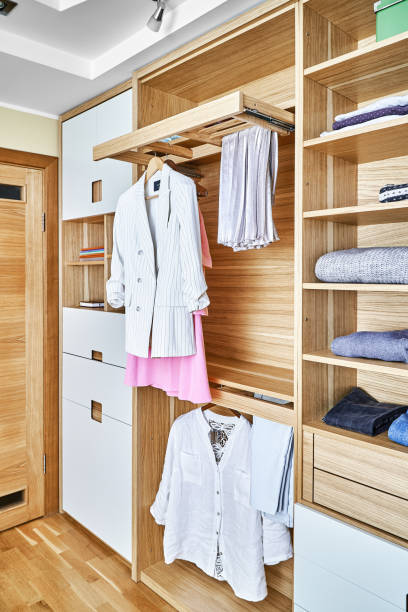 istock Modern wardrobe with clothes hanging on slide out racks and folded on the shelves. Modern furniture 1285957756
