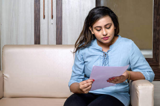 istock Frustrated woman using laptop and reading documents at home 1285961292