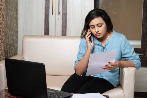 istock Frustrated woman using laptop and reading documents at home 1285961301