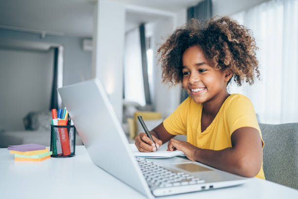Schoolgirl studying with video online lesson at home. Young student watching lesson online and studying from home. Girl using laptop for online lessons. Homeschooling and distance learning concept. 8 9 years photos stock pictures, royalty-free photos & images