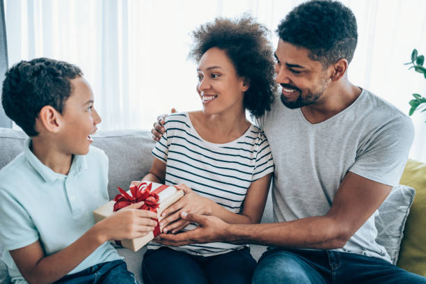 istock Cheerful child receiving a gift from his parents. 1285962635
