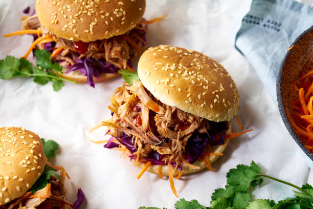 Pulled pork burgers Pulled pork burgers with pickled and fresh vegetables and coriander on white tiled background shredded photos stock pictures, royalty-free photos & images