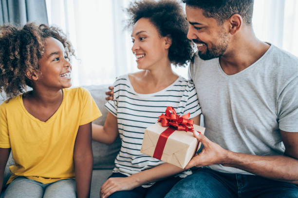 istock Cheerful child receiving a gift from her parents. 1285963564