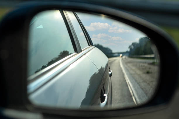 reflexión en el espejo lateral de un coche que conduce en la carretera, coche visible en el reflejo. - rear view mirror car mirror sun fotografías e imágenes de stock