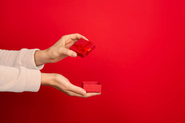 istock Female hand hold open red small jewelry box on red background. 1285965412