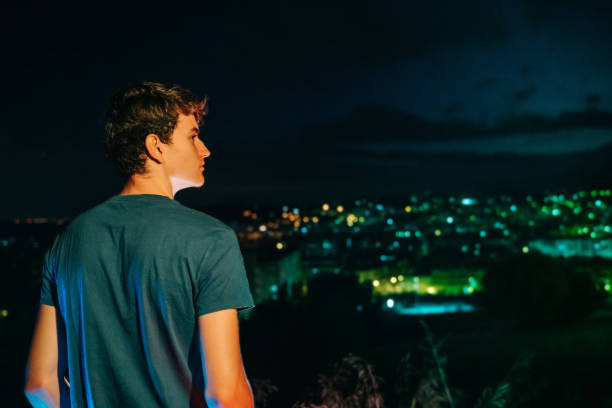 istock Teenage boy looking at city lights at night 1285965714