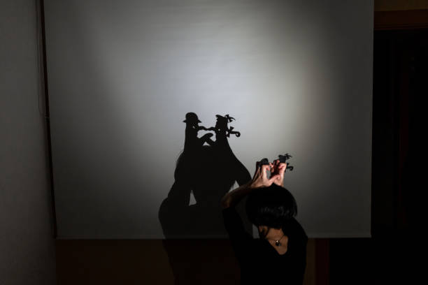 play shadow projected on a white screen. the person's hands shape two little people talking and kissing