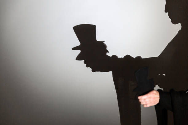 istock play shadow projected against a white background. a old man with hat. 1285967358