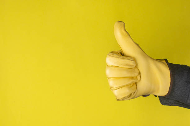 istock Thumbs up. Gloved hand on a yellow background. 1285968374
