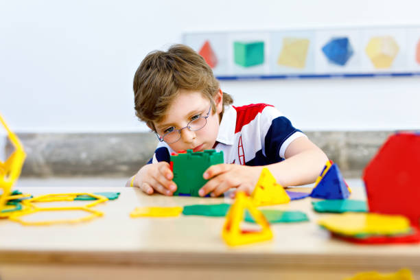 istock Happy kid boy with glasses having fun with building and creating geometric figures, learning mathematics and geometry 1285969325