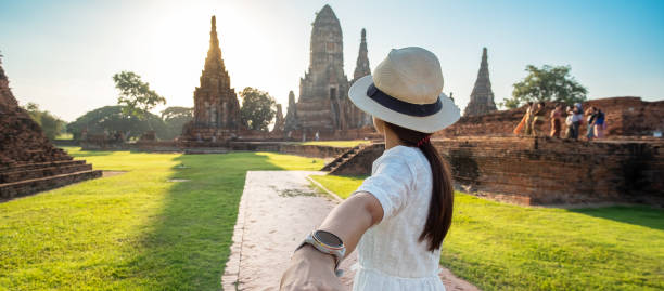 tourist woman in weißen kleid hält ihren mann von hand und zu fuß zu alten stupa in wat chaiwatthanaram tempel in ayutthaya historical park, sommer, zusammen, folgen sie mir, asien und thailand reisen - wat chaiwattanaram stock-fotos und bilder