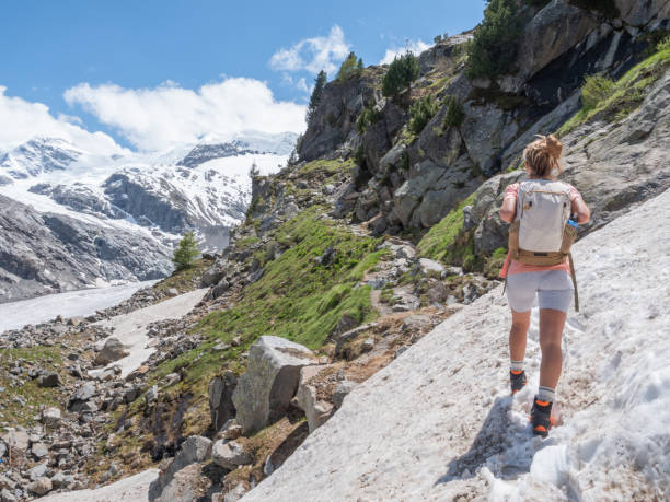 la senderista femenina cruza el camino nevado para llegar al sendero - switzerland hiking boot outdoor pursuit recreational pursuit fotografías e imágenes de stock