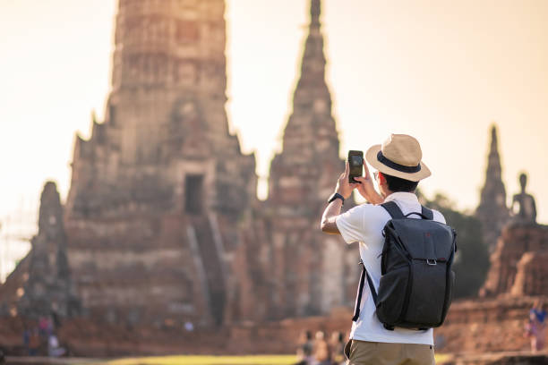 istock Happy tourist man with backpack Taking Photo by mobile smartphone, during visiting in Wat Chaiwatthanaram temple in Ayutthaya Historical Park, summer, solo, Asia and Thailand travel concept 1285969817