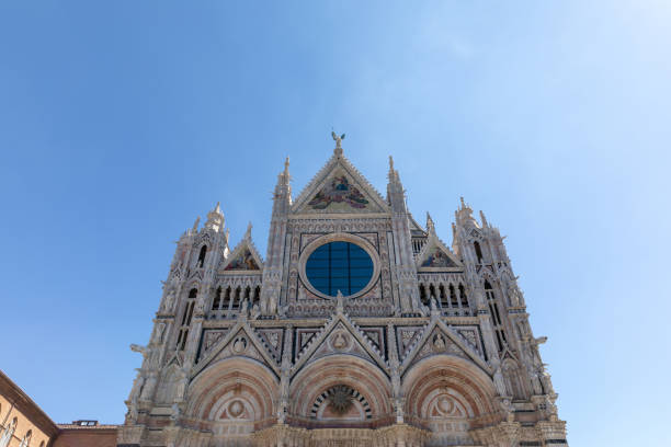 Siena Cathedral interior view, looking up to black and white stripe marble columns, arches with pope busts on spandrels, and vaulted, star decorated blue ceilings. The Duomo di Siena building is majestic Tuscan architecture, an Italy travel destination and tourist attraction for European and Italian Catholic religion, history and culture.