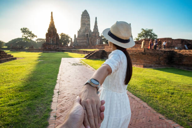 tourist woman in weißen kleid hält ihren mann von hand und zu fuß zu alten stupa in wat chaiwatthanaram tempel in ayutthaya historical park, sommer, zusammen, folgen sie mir, asien und thailand reisen - wat chaiwattanaram stock-fotos und bilder