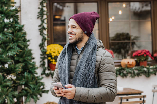 istock Young man holding smart phone outdoors during Christmas 1285973509
