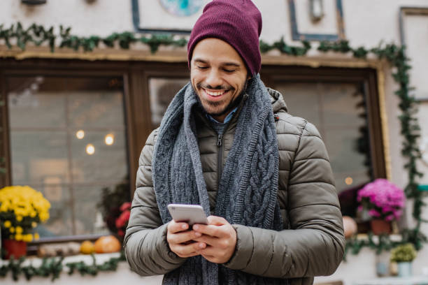 istock Young man holding smart phone outdoors during Christmas 1285973549