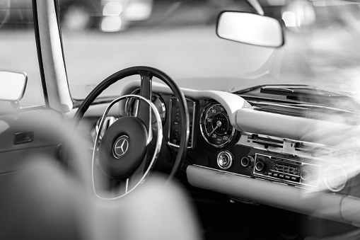Hamburg, Germany - November 15.2020: look through the side window onto the steering wheel and dashboard in a Mercedes Benz classic car oldtimer, parked somewhere in Hamburg, downtown. Black and white image