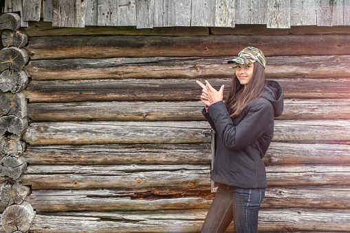 Girl pointing finger of both hands, a wooden wall the background, copy space.